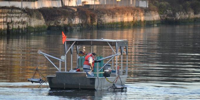 Two people on board a boat with "water guns" attached on metal arms off the front of the boat.