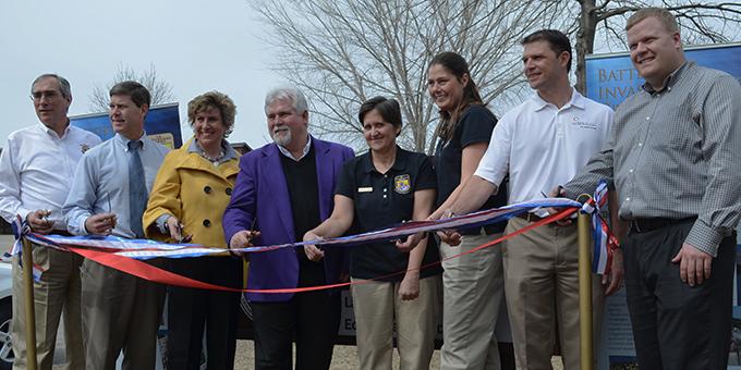 A group of people holding scissors stand in front of ribbons.