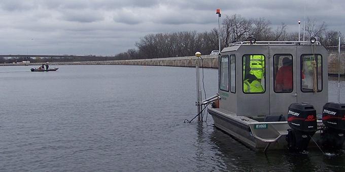 A boat with double engines sits in the water. Another boat can be seen in the distance.